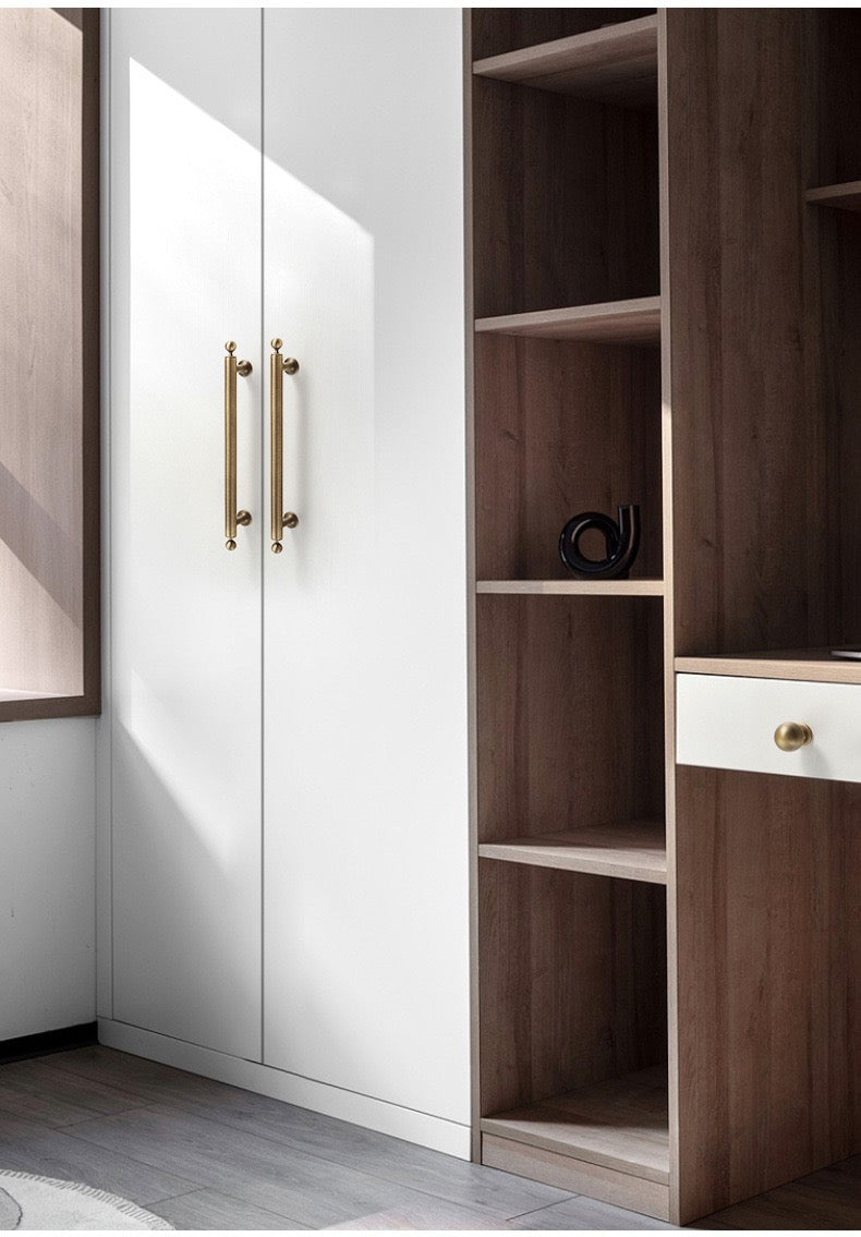 Aged bronze bar handles installed on white wardrobe