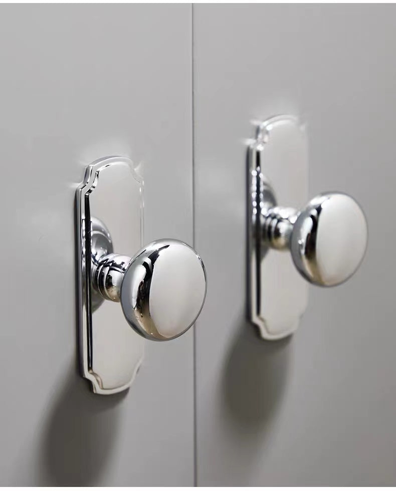 Close-up of round silver door handles on a light gray cabinet door