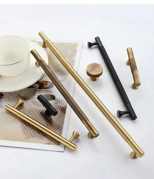 Set of gold, black, and bronze cabinet handles on a white surface with a magazine underneath.