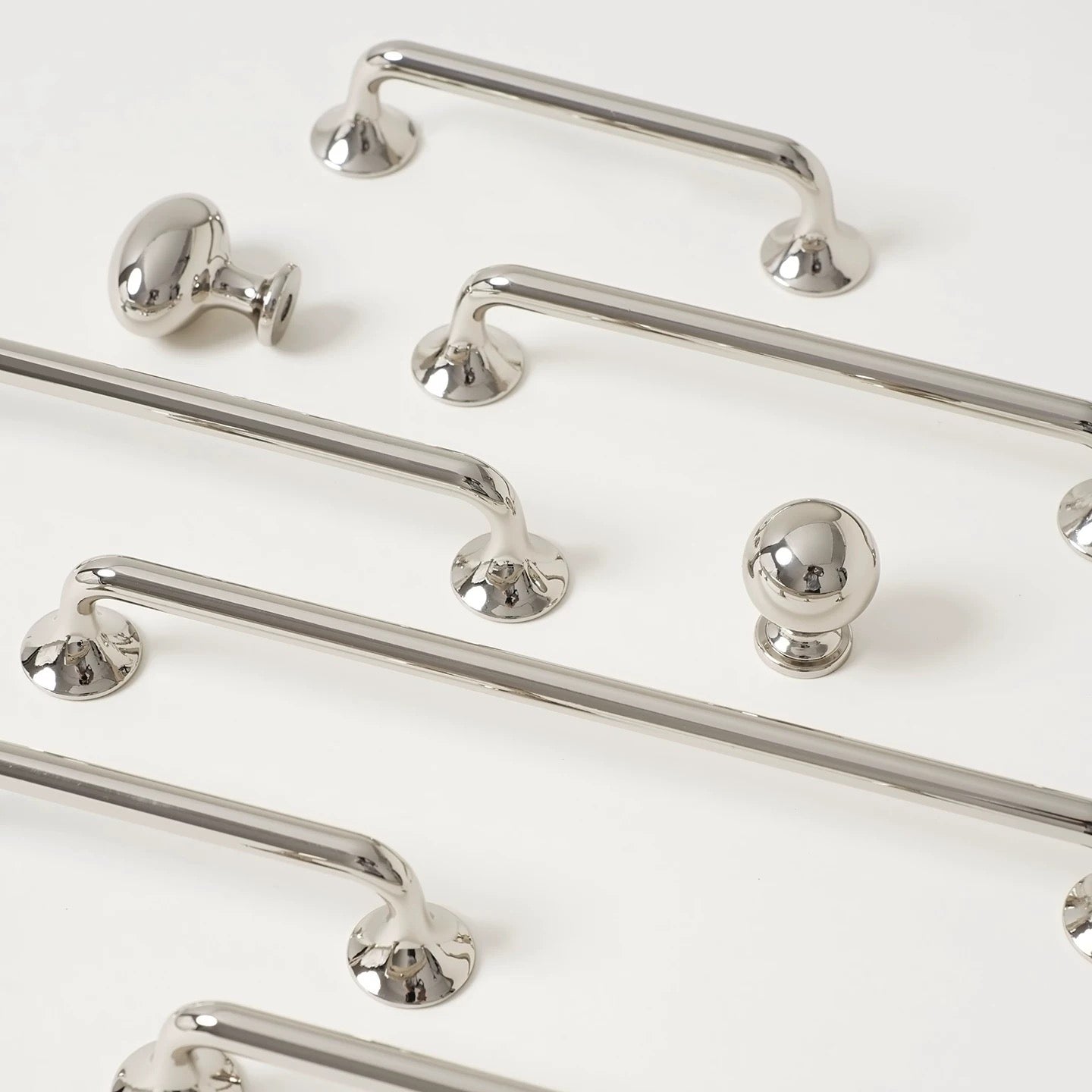 Set of polished silver cabinet d shaped handles and knobs on a white background
