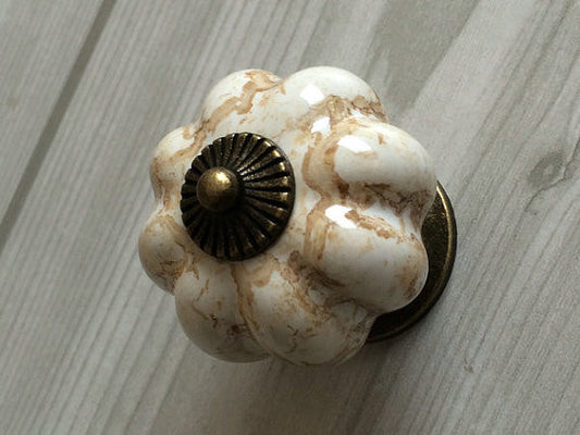 Decorative door knob with marble-like finish and brass center on a wooden surface