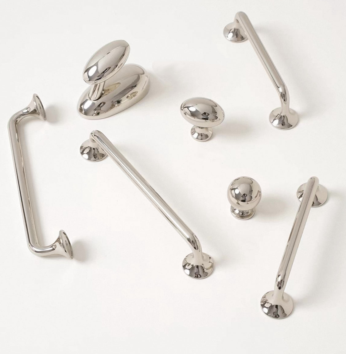 Collection of polished nickel cabinet handles and knobs on a white background