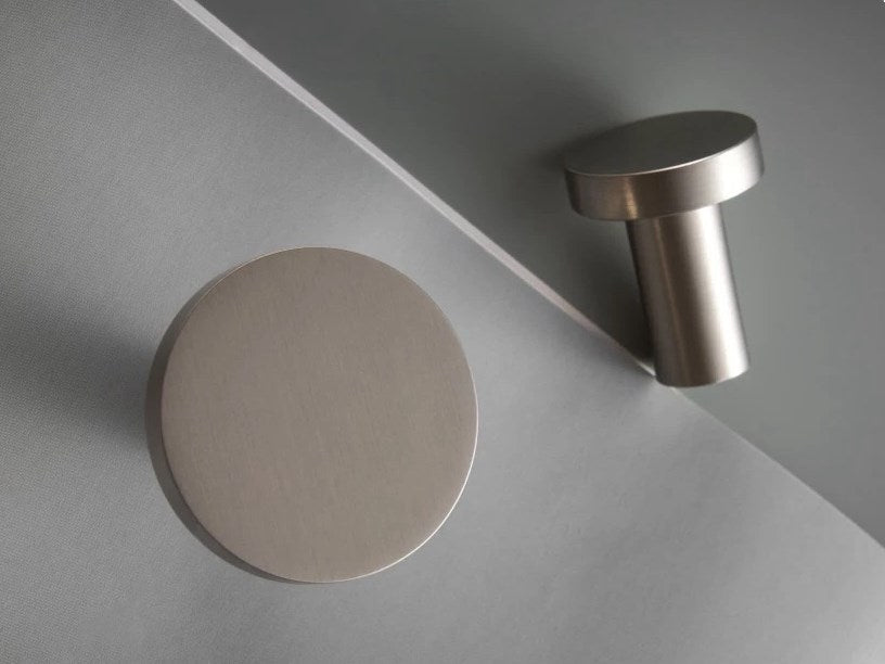 Two nickel round knobs on a gray surface