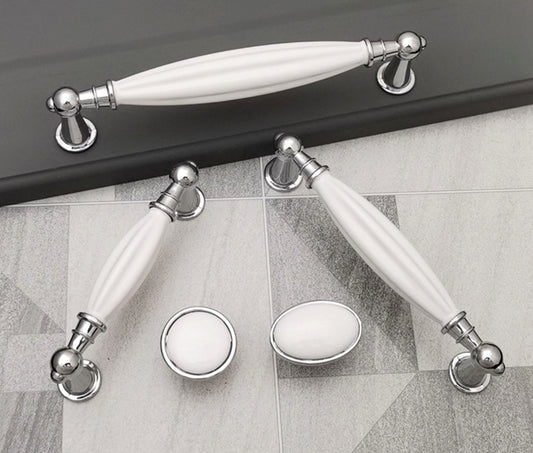 Set of white ceramic handles with silver metal accents on a tiled floor.