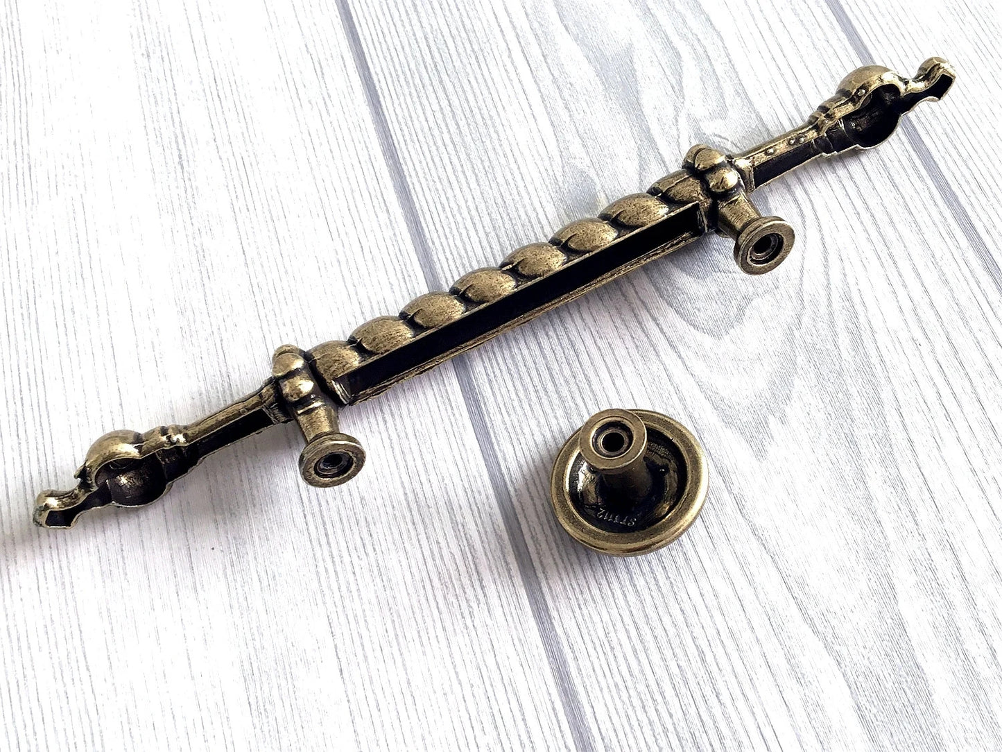 Decorative metal handle on a white wooden surface