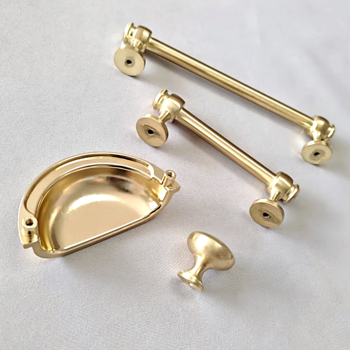Set of gold cabinet handles and pulls on a light gray background
