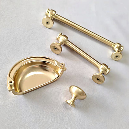 Set of gold cabinet handles and pulls on a light gray background