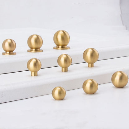 Gold spherical knobs on a white surface