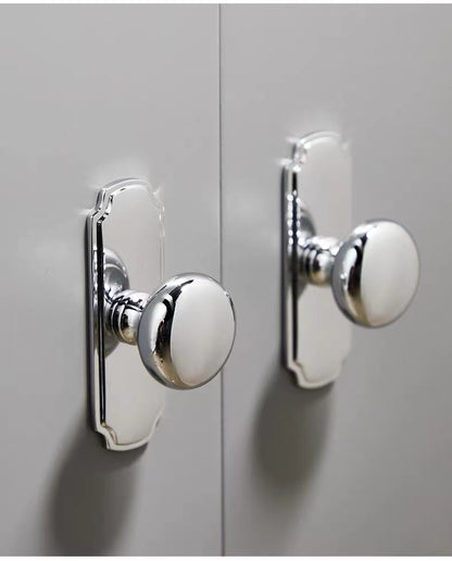 Close-up of round silver door handles on a light gray cabinet door