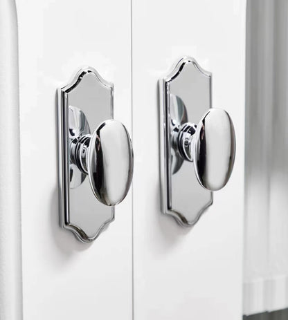 Close-up of two polished chrome oval door pulls on a white door.
