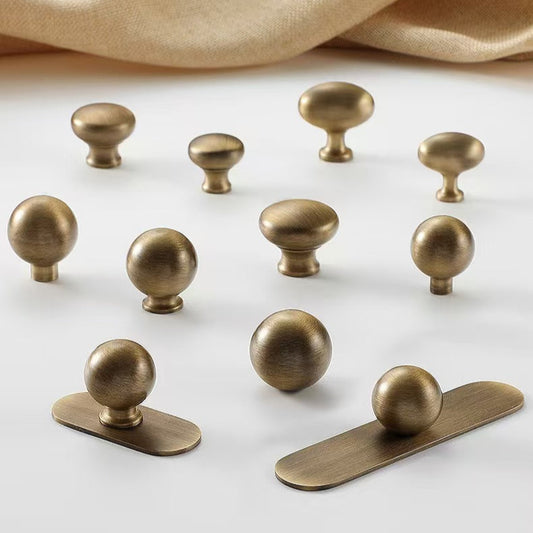 Set of antique bronze drawer knobs on a white surface with a beige fabric background