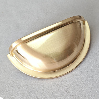 Gold cup drawer pull on a gray background
