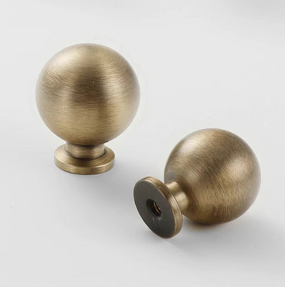 Two brass antique bronze spherical cabinet knobs on a white background