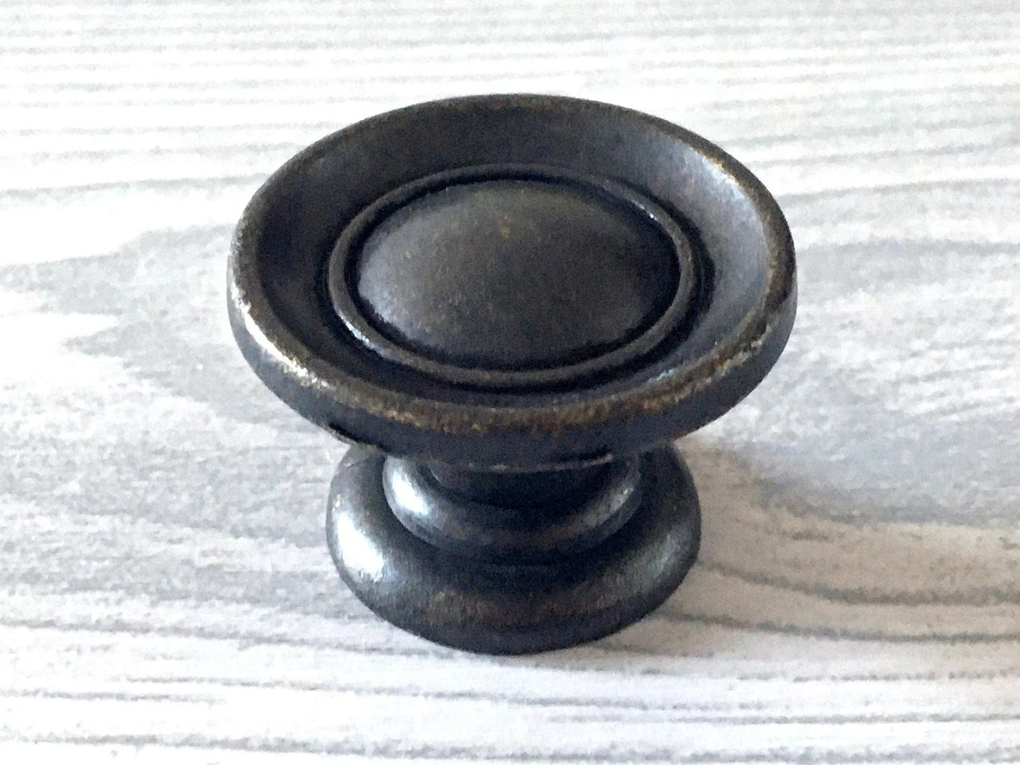 Antique bronze cabinet knob on a light wood surface