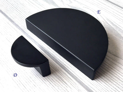 Two black semi-circular drawer pulls on a light wooden surface