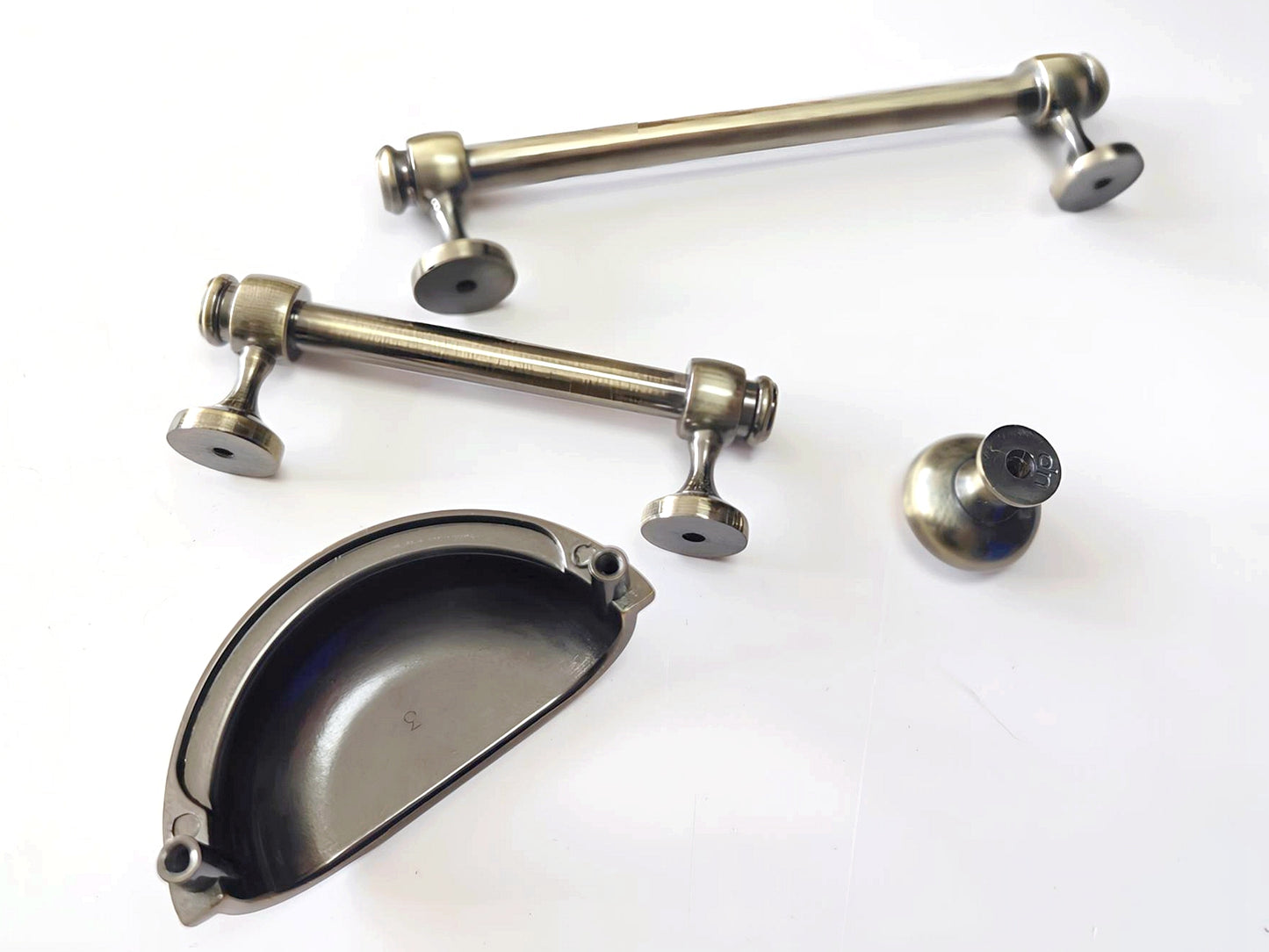 Collection of antique bronze cabinet bar handles and knobs on a white background