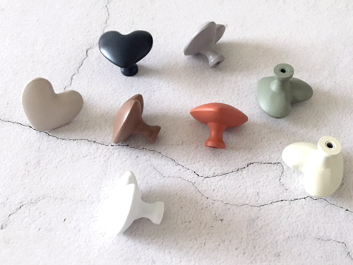 Set of heart shaped knobs in various shapes and colors on a textured white surface