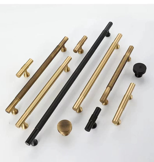 Set of gold, black, and bronze cabinet handles on a white background