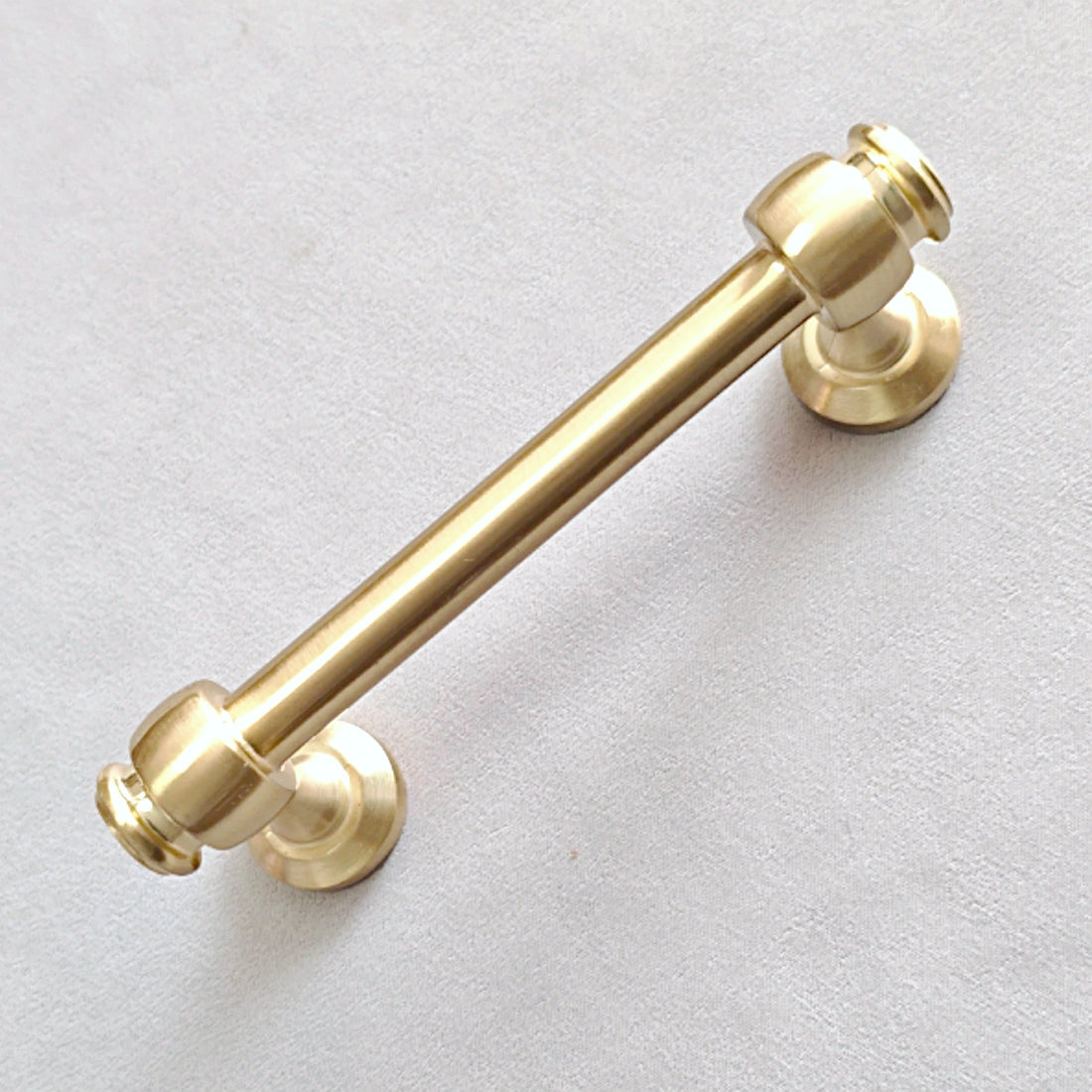 Gold cabinet round bar handle on a light gray background