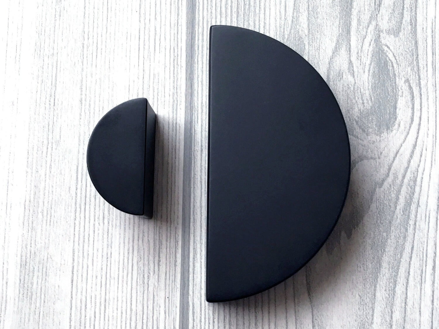 Black half-circle cabinet pulls on a light wood surface