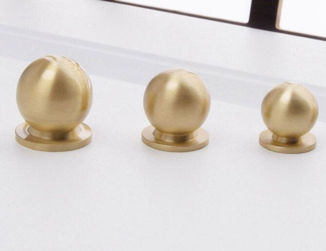 Three gold spherical knobs with large base on a white background