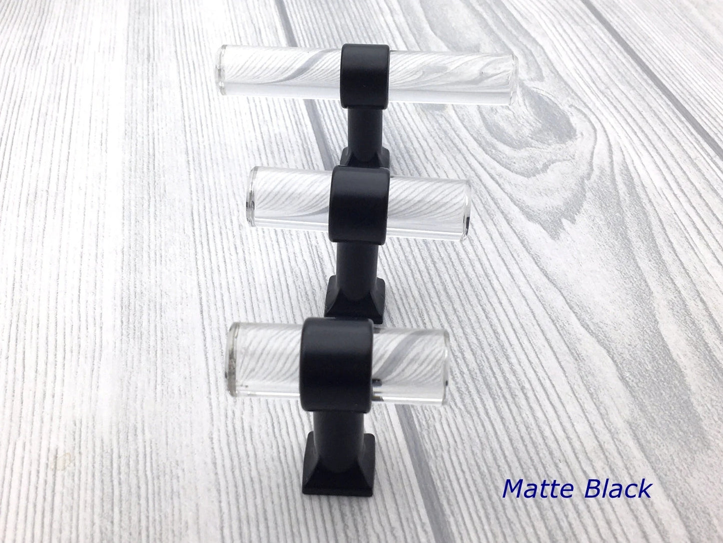 Set of three black and clear lucite cabinet knobs on a textured white background