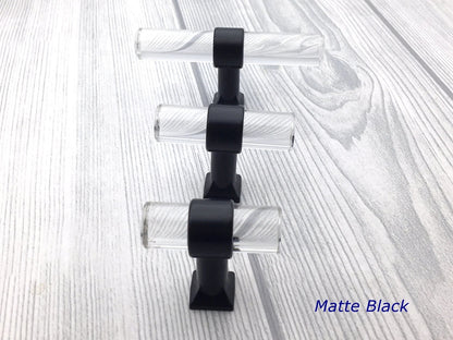 Set of three black and clear lucite cabinet knobs on a textured white background