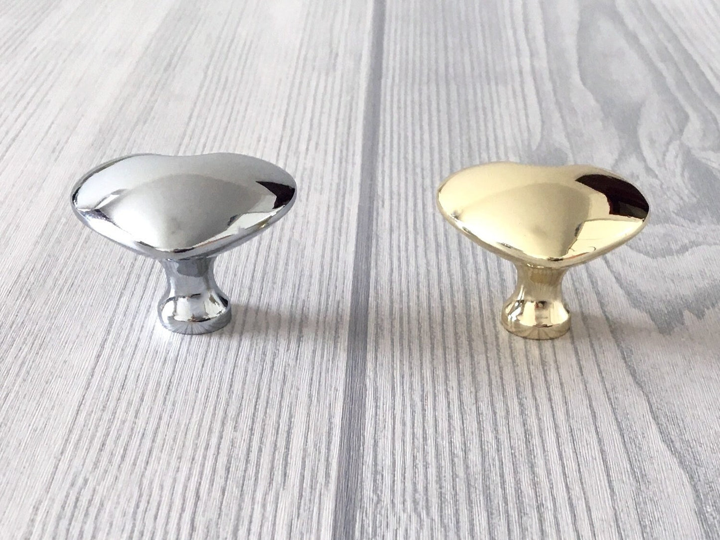 Two metallic heart shaped cabinet knobs, one silver and one gold