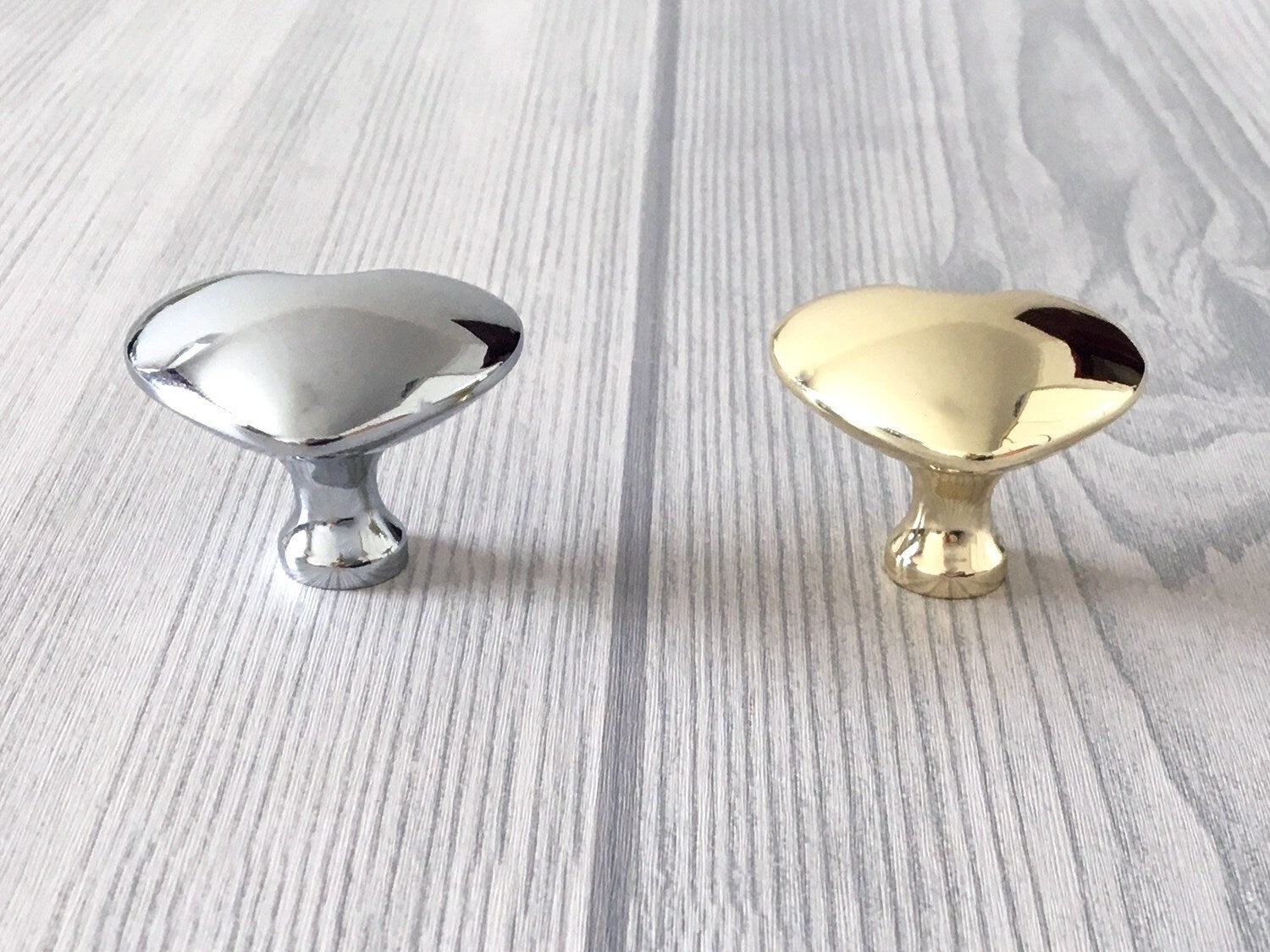 Two metallic heart shaped cabinet knobs, one silver and one gold