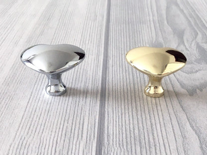 Two metallic heart shaped cabinet knobs, one silver and one gold