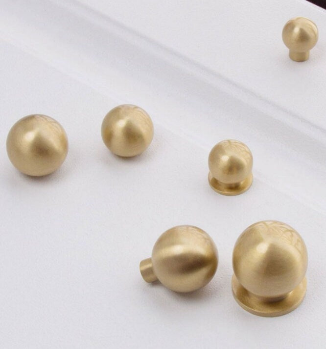 Set of gold spherical drawer pulls on a white background