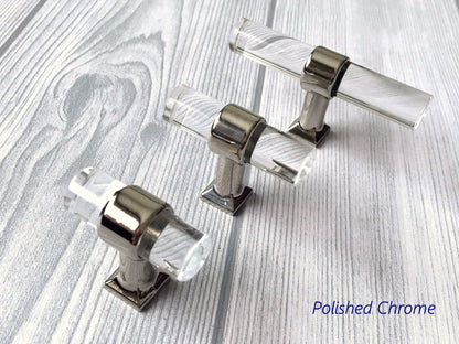 Polished chrome and acrylic cabinet handles on a wooden surface