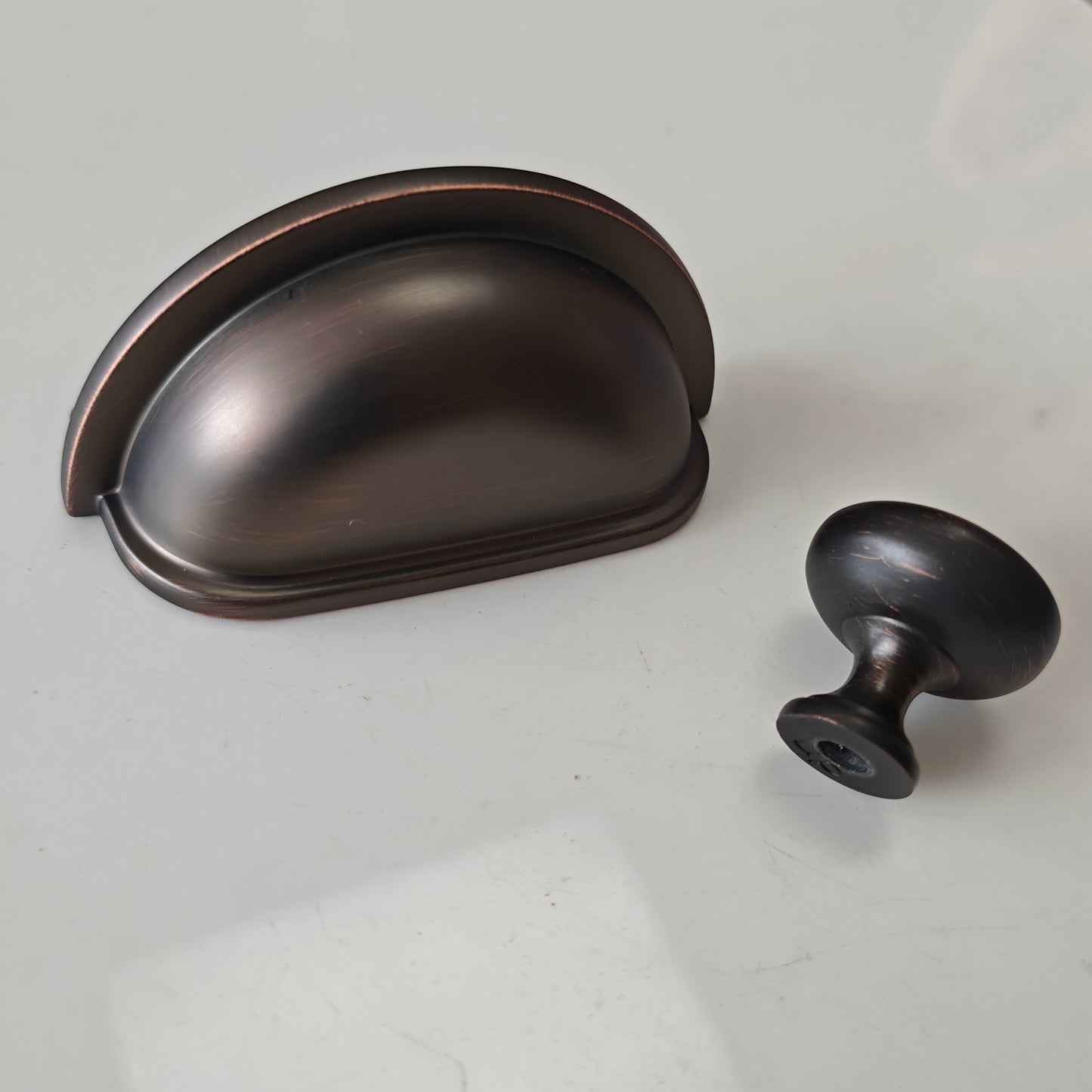 oil rubbed Bronze cabinet cup pull and knob on a white background