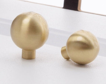 Two gold spherical knobs on a white surface