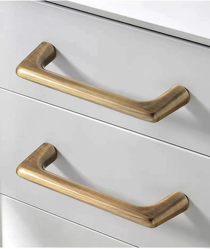 Two antique bronze cabinet D handles on a white drawer