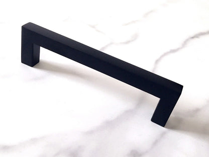 Black cabinet square handle on a white marble surface