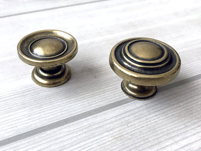 Two brass antique bronze cabinet knobs on a white wooden surface