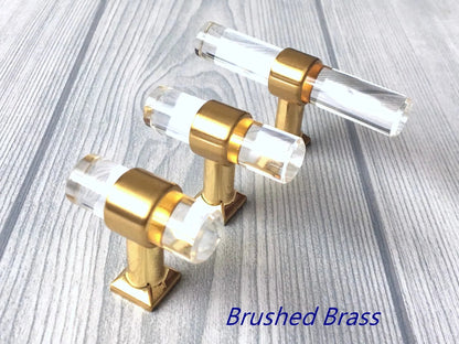 Gold and clear acrylic cabinet knobs on a light wooden surface
