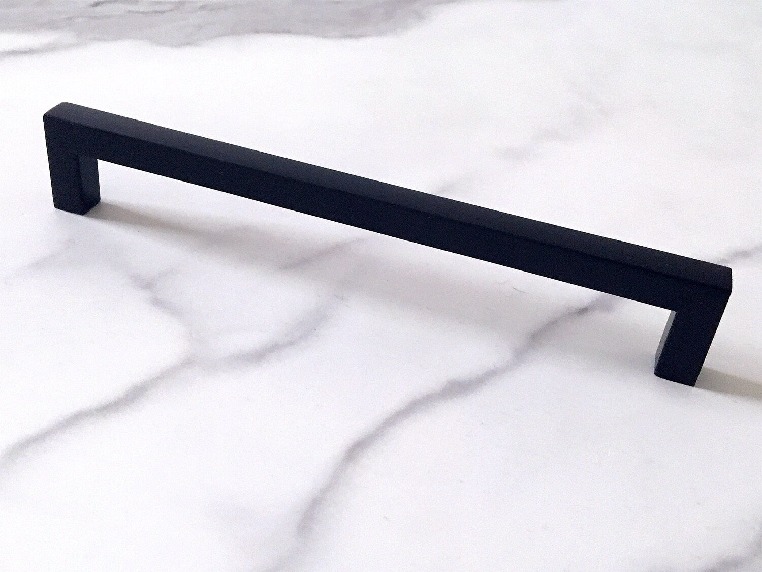 Black cabinet square handle on a marble surface