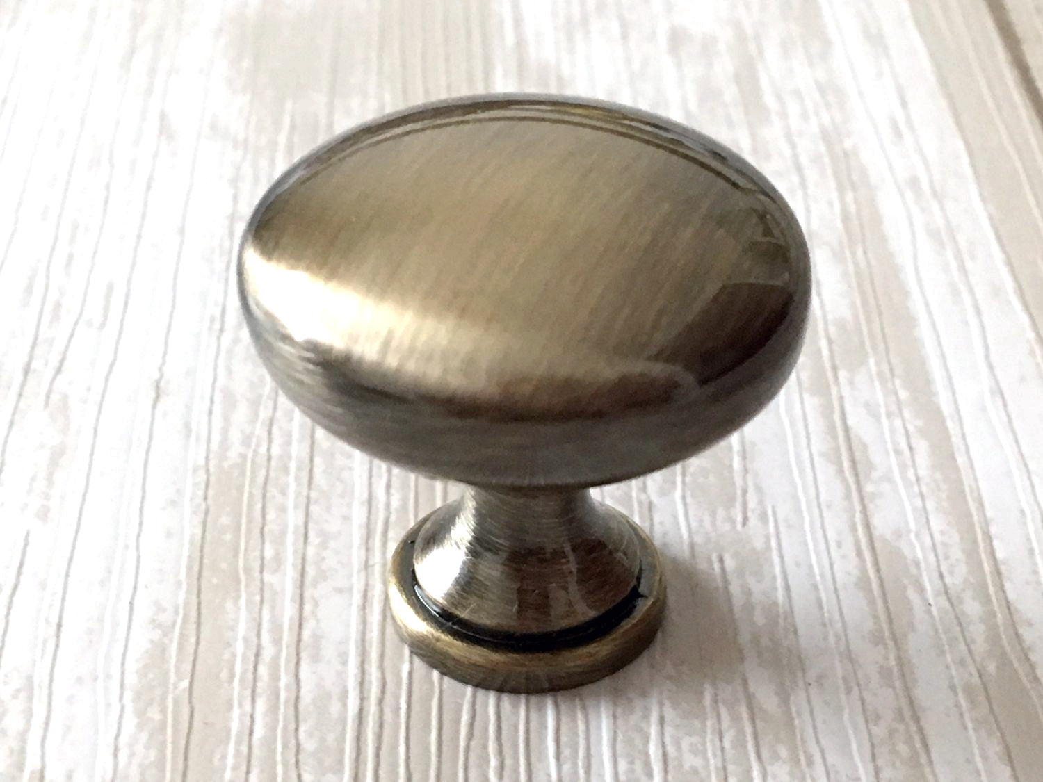 Metallic cabinet knob on a light wood surface
