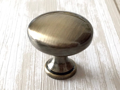 Metallic cabinet knob on a light wood surface