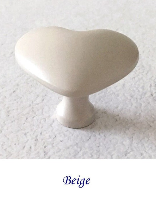 Beige heart shaped cabinet knob on a textured white background