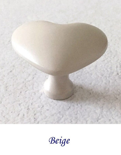 Beige heart shaped cabinet knob on a textured white background