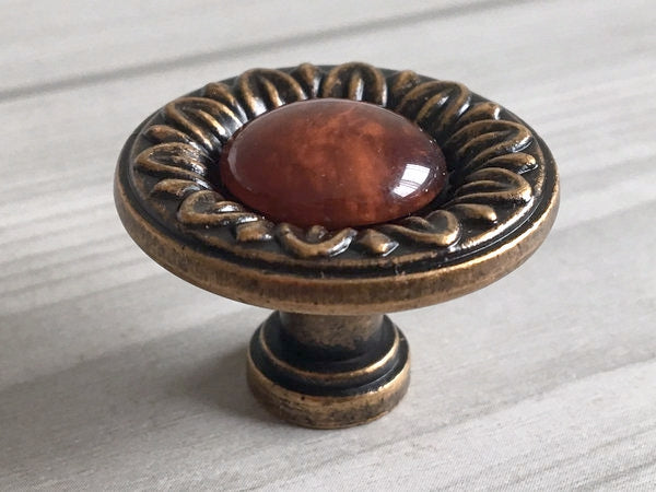 Decorative cabinet knob with red resin gemstone on a light wooden surface