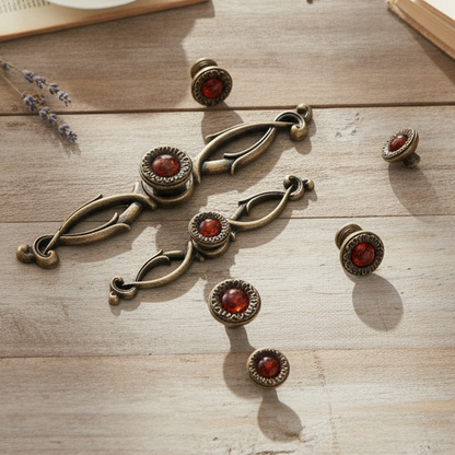 Decorative bronze knobs with red gemstones on a wooden surface