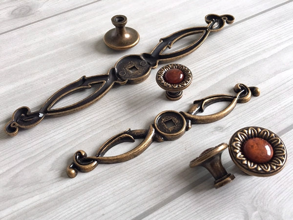 Set of vintage-style brass cabinet handles and knobs on a light wooden surface