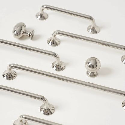 Set of polished silver cabinet d shaped handles and knobs on a white background