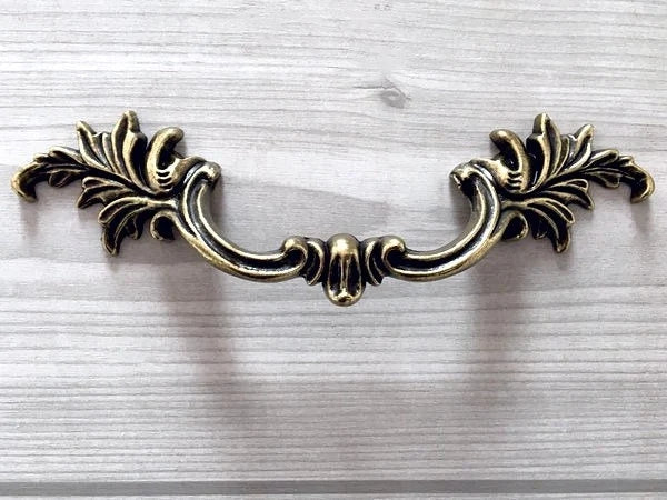 Decorative retro brass cabinet handle on a white background