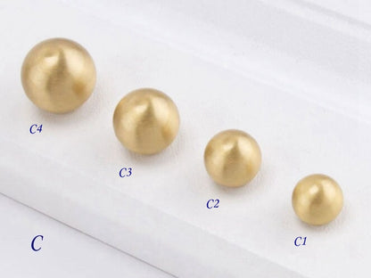 Four gold globed cabinet knobs  of different sizes on a white background