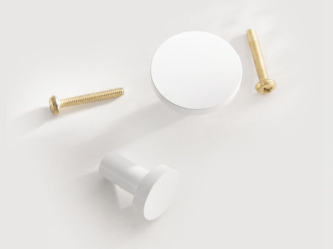 White cabinet knobs with screws on a light gray background